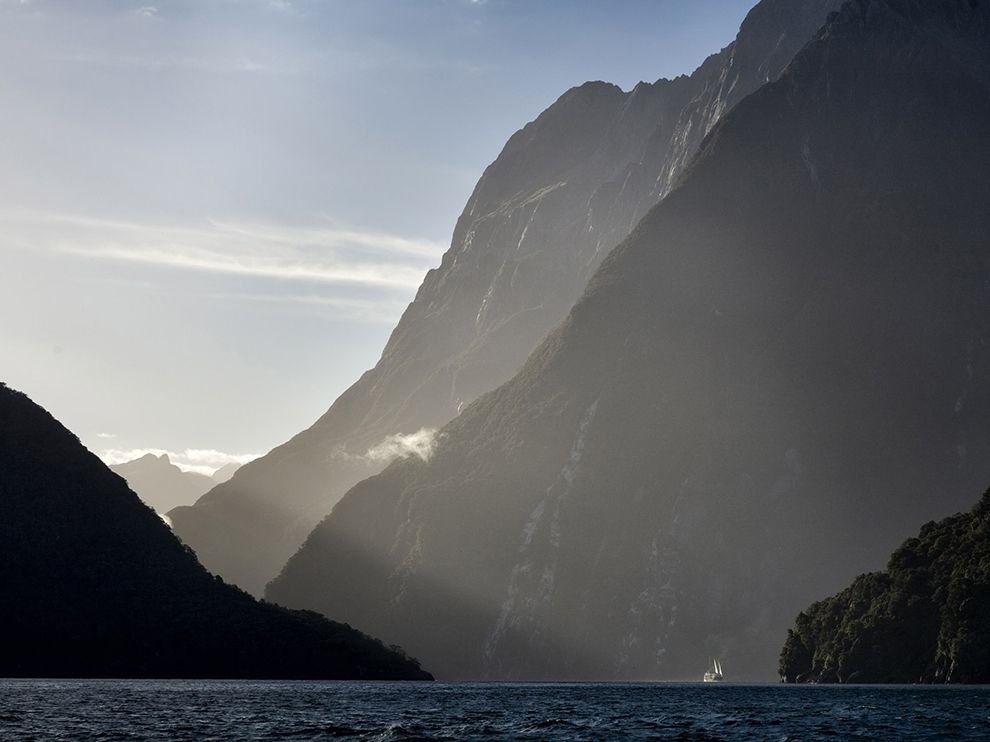 Milford Sound, New Zealand: Con thuyền thật nhỏ bé trước những vách đá sừng sững trên mặt nước sâu thẳm. Milford Sound là một vịnh hẹp hình thành do hoạt động băng hà.