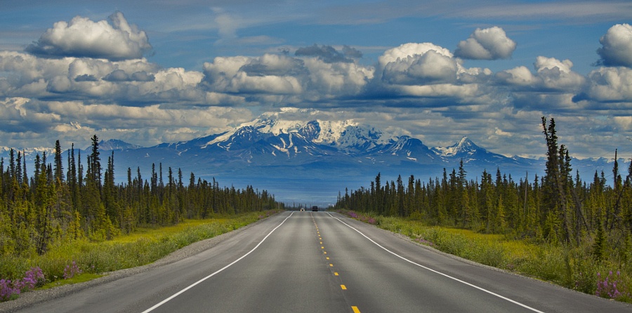 Con đường tuyệt đẹp đi qua Wrangell-St Elias, với cây cỏ hai bên và dãy núi mây phủ phía xa.