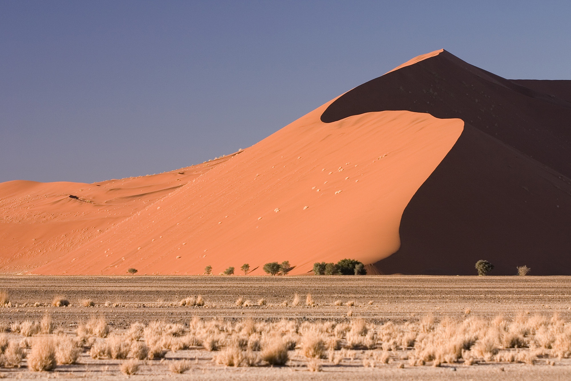 Các đụn cát Sossusvlei, Namibia: Đây là điểm đến hấp dẫn nhất Namibia, với những đụn cát màu đỏ cam rực rỡ nổi bật trên trời xanh. Các đụn cát đã phải mất hàng triệu năm để hình thành. Cát bụi từ sông Orange chảy ra Đại Tây Dương, xuôi xuống phía bắc và được sóng đẩy lại vào bờ. Ảnh: Luxurytravel.