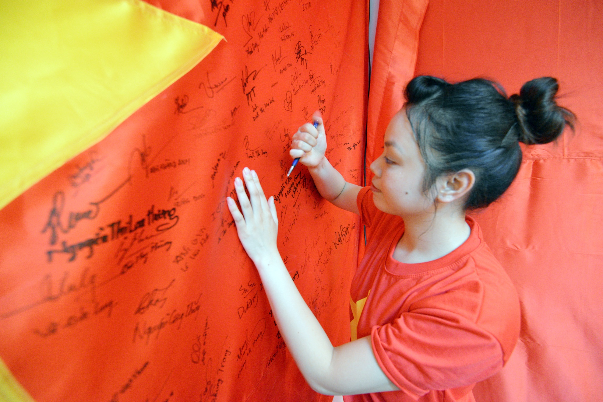 Bạn Thanh đang ký tên của mình lên lá cờ cỡ lớn đặt ngay trong studio.
