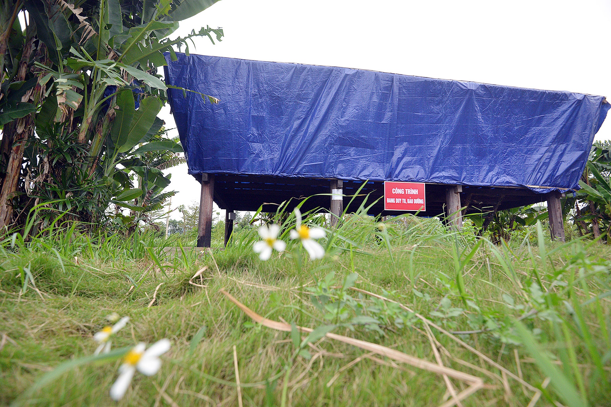 Khu nhà Dân tộc Chứt bị cháy năm 2013 được Ban quản lý làng Văn hóa du lịch bịt lại bằng tấm bạt màu xanh. Phía ngoài treo tấm biển 