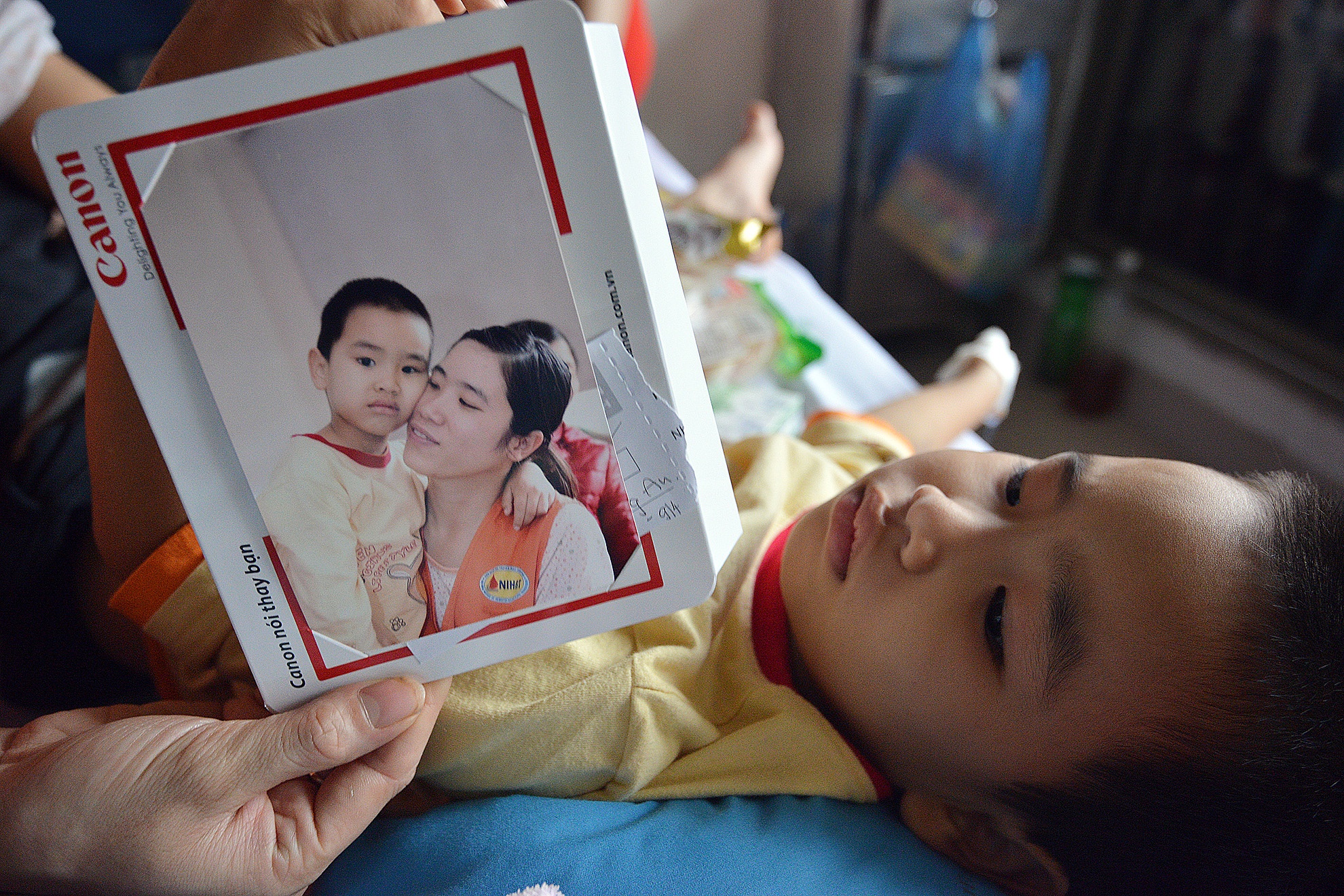  Một bé trai do đang truyền hóa chất nên tỏ ra khá mệt. Mẹ bé cho biết, lúc chụp ảnh cháu cũng mệt lắm, nhưng do từ bé thích chụp ảnh nên vẫn dậy để cho các cô chú bấm máy.