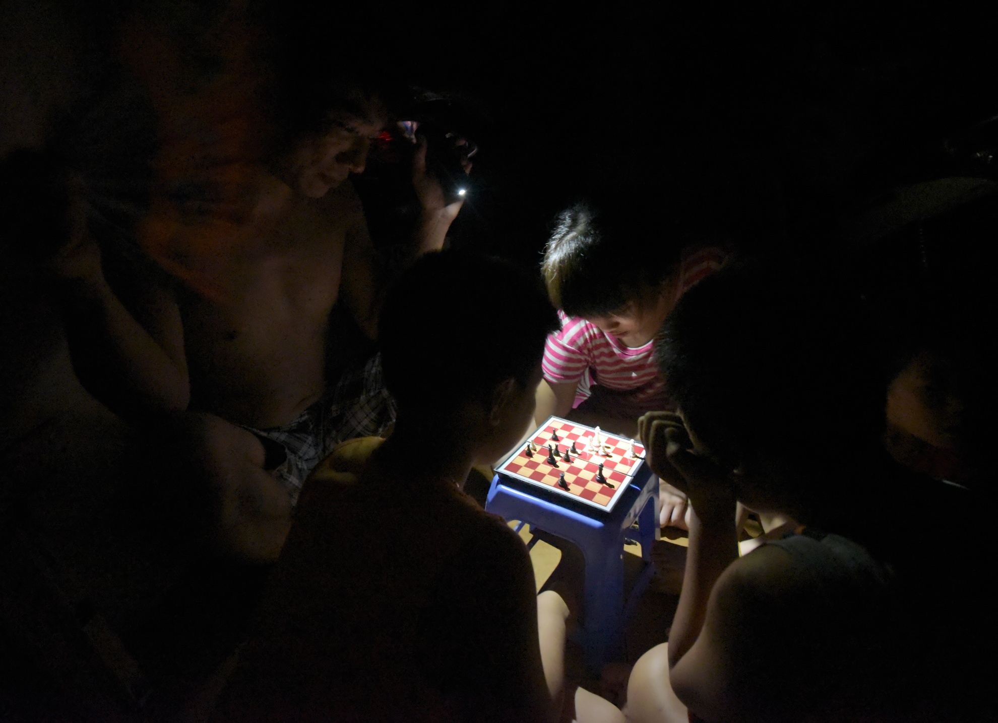 Gia đình anh cho trẻ con chơi cờ dưới ánh nến.