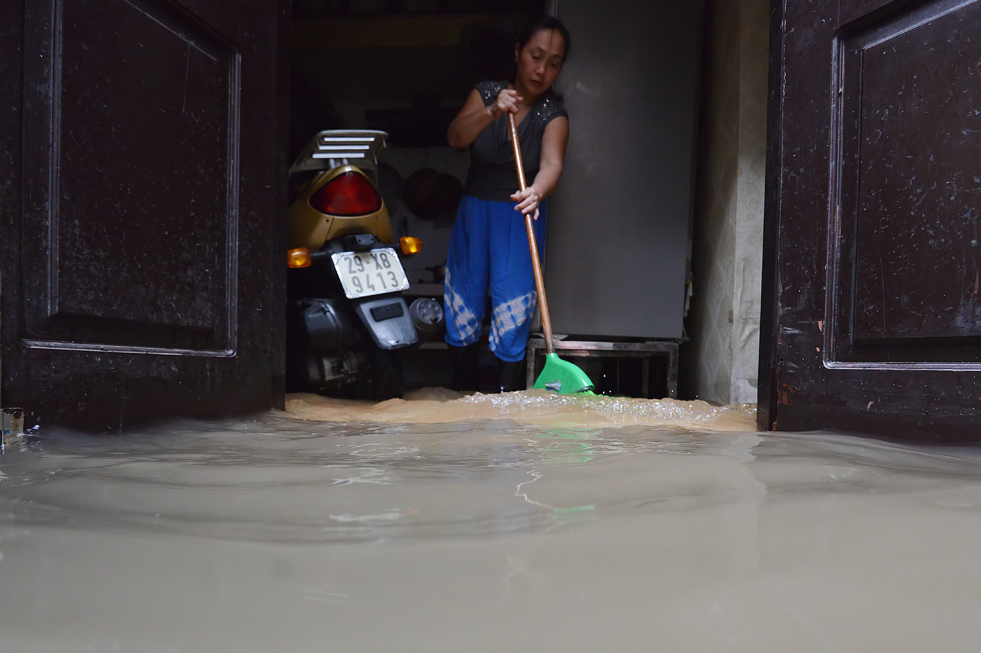  Nước rút rất chậm nên người dân chỉ còn biết dùng chổi, chậu tát nước ra khỏi nhà. 