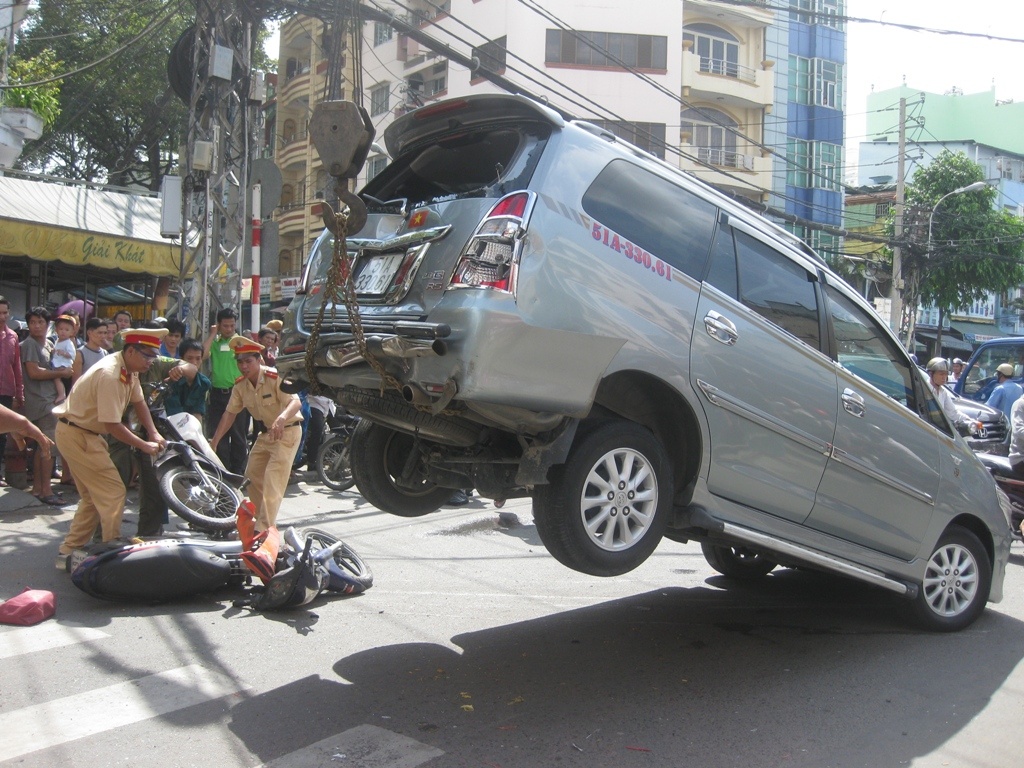 Nhan vien rua xe lai o to cua khach cuon 2 xe may vao gam hinh anh