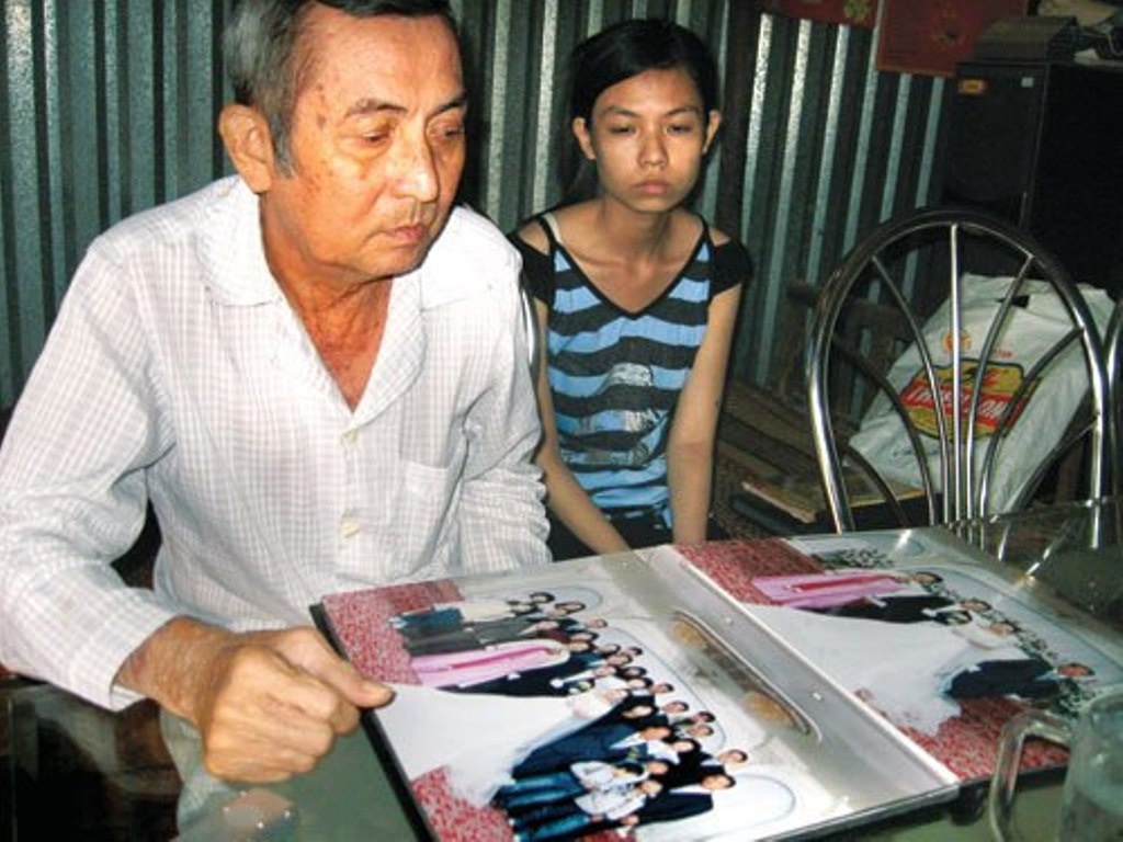 Ông Linh buồn bã xem lại ảnh cưới của con gái.