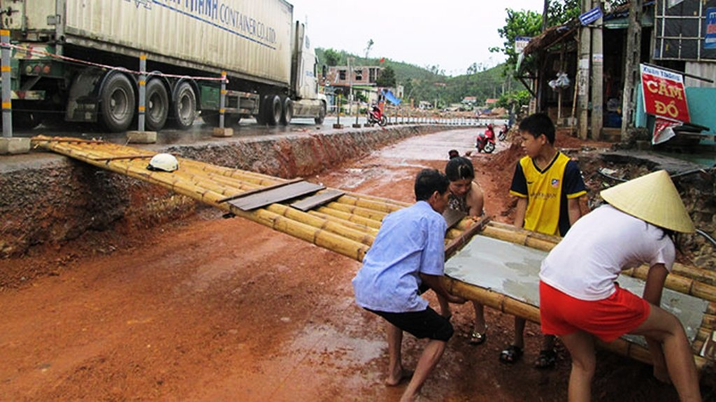 Cả nhà ông Phạm Xuân Tiến (ở Lý Hòa, xã Hải Trạch, huyện Bố Trạch, Quảng Bình) phải bắc cầu tre gần 4m ra quốc lộ 1 mới mong có khách vào mua hàng