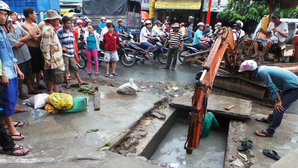 Sau cơn mưa lớn chiều 8/9, một nắp cống gần nơi bé Tỷ bị cuốn trôi bị bị sụp xuống cống, phải huy động xe múc để tìm nắp.