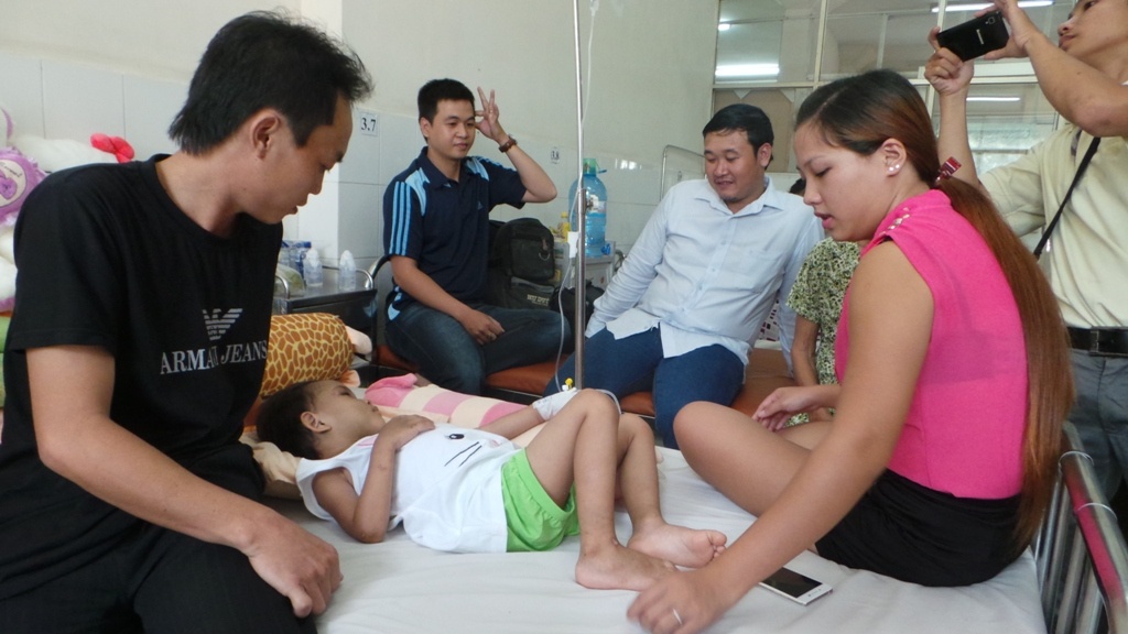 Bé Ngân bên cạnh cha ruột cùng cha mẹ nuôi là chị Nhàn và anh Hưng (áo trắng).