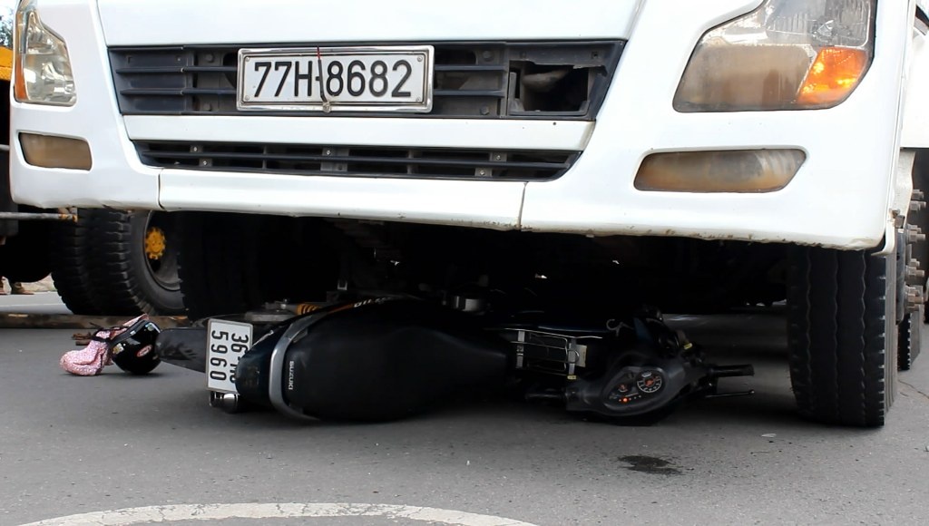 Thi the 2 co gai mac ket duoi banh xe tai hinh anh