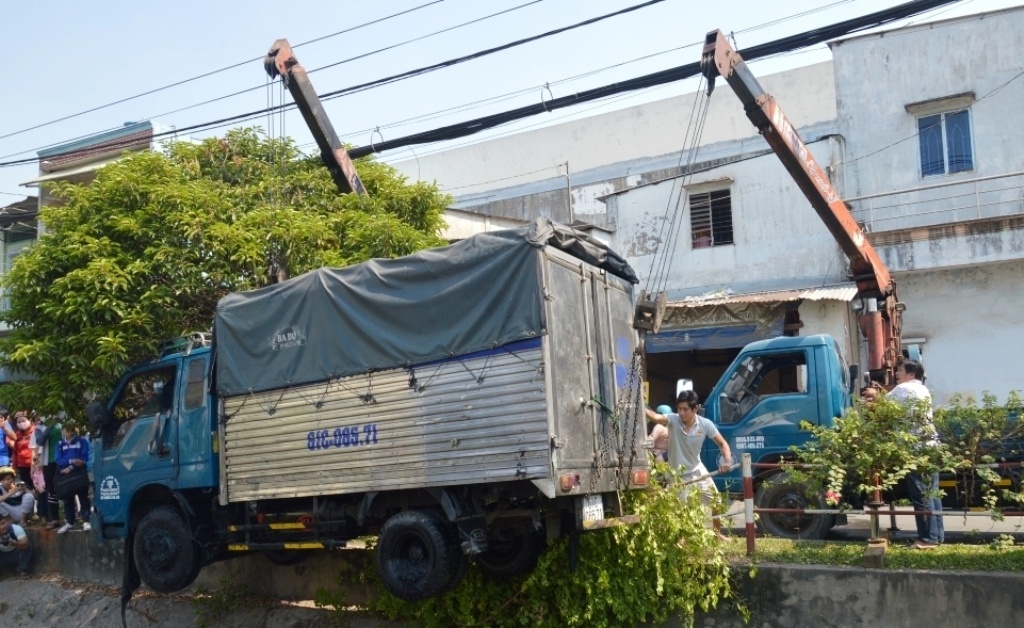 Hai xe cứu hộ di dời xe tải khỏi dòng kênh thối.