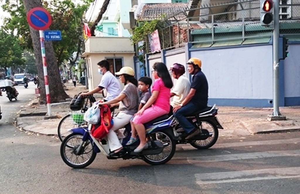 Nhiều phụ huynh học sinh chưa chấp hành cho con em mình đội mũ bảo hiểm khi ra đường.