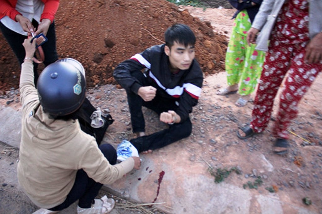 Một nạn nhân tại thị trấn Đắk Hà bị xe điên tông đang ngồi bên vệ đường đợi xe cấp cứu.