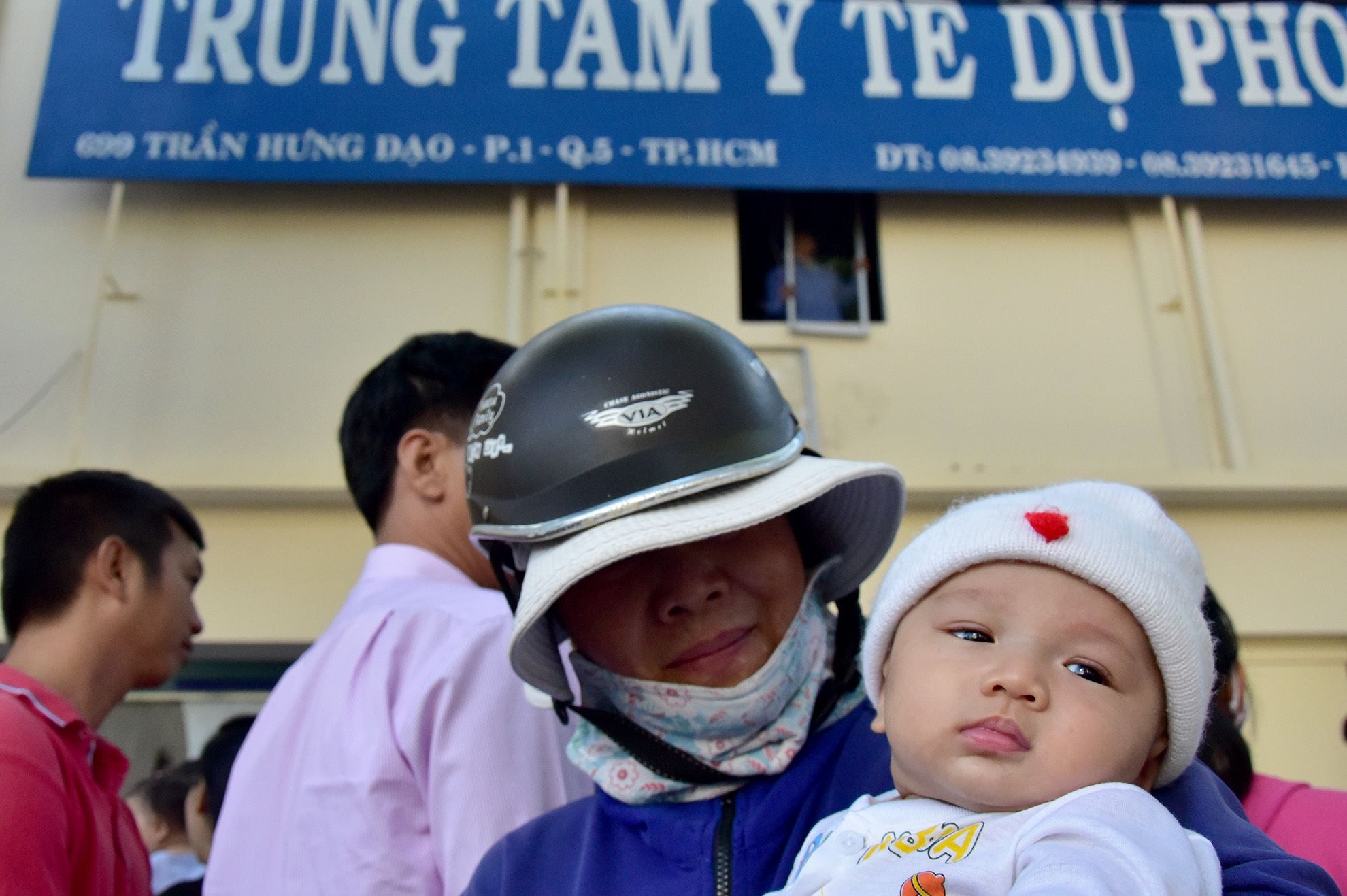 Một em bé được đưa đến từ sớm để chờ được tiêm.