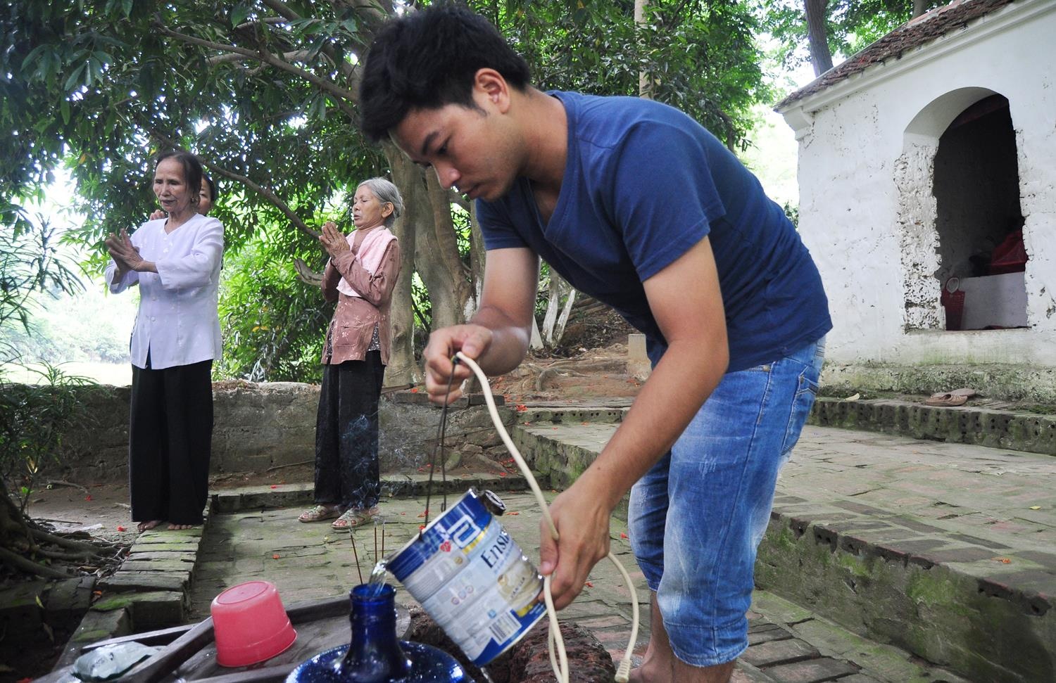 Anh Quang (30 tuổi), con trai bà Toán đang múc nước ở giếng xin sữa về cho vợ uống.