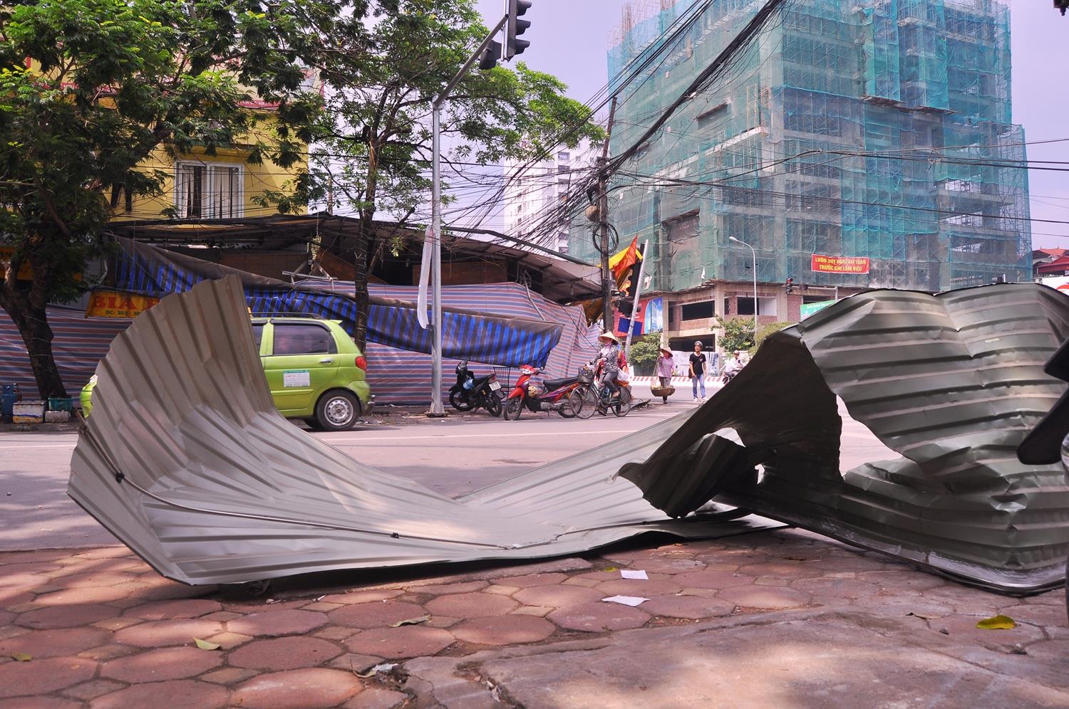 Những mảnh tôn trên mái bị hất văng ra giữa đường được người dân gom gọn vào vỉa hè trước đó.
