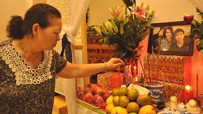 Bức ảnh rạng rỡ của chị Nguyễn Ngọc Minh và hai con giờ đây trở thành ảnh thờ. Mẹ chị Minh - bà Quản Thị Phong - lòng đau như cắt khi thắp hương cho con, cháu - Ảnh: Quang Thế.