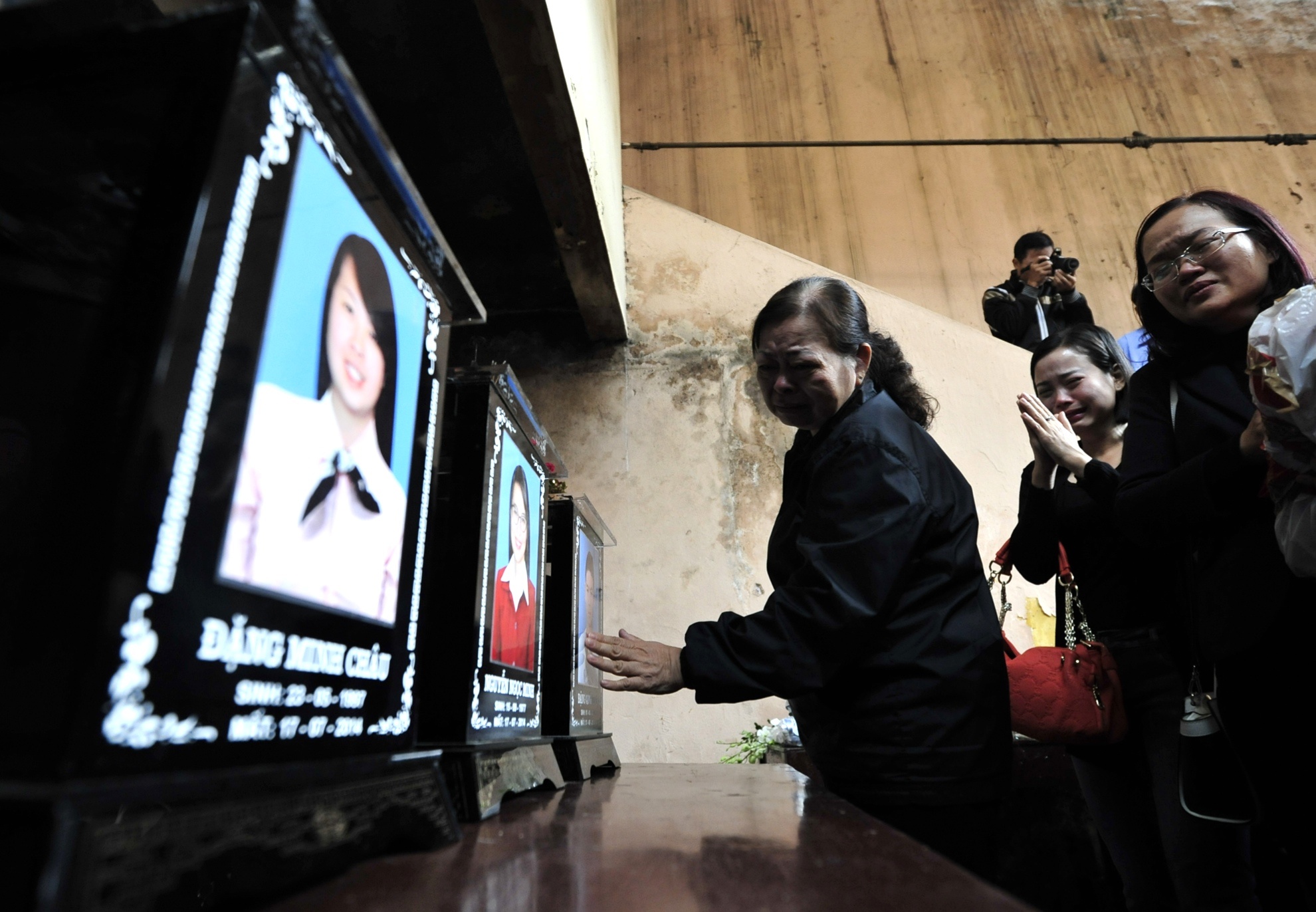 Bà Phong (mẹ chị Minh) khóc nấc tiến lại ban thờ dùng tay vuốt gương mặt con gái và cháu ngoại sau bao ngày mong ngóng. Ảnh: Hoàng Anh.