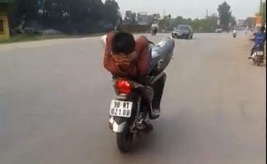 nh thanh niên không đội mũ bảo hiểm, nằm ngửa, lái xe bằng chân trên quốc lộ -