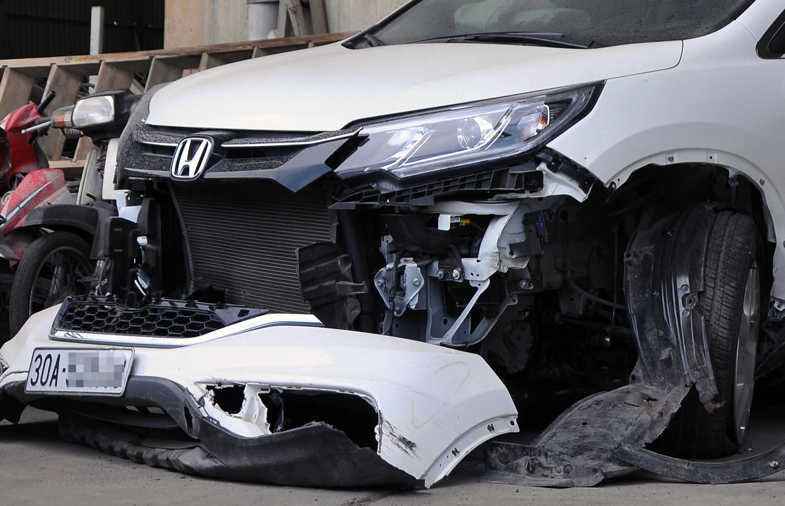 Chiếc Honda 7 chỗ màu trắng bị hư hỏng phần trước xe sau một vụ tai nạn giao thông được tập kết phục vụ công tác điều tra.