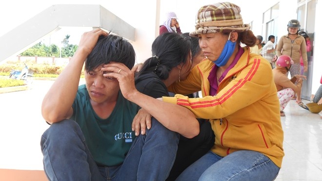 Bố mẹ cháu bé tử vong đau buồn trong khi chờ công an khám nghiệm tử thi. Ảnh: M. Quý.