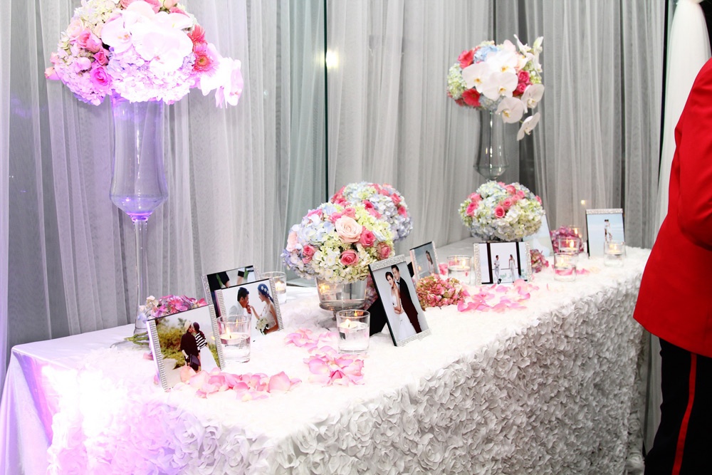 Tại khu vực sảnh của nhà hàng, anh dùng một bàn dài để trưng hoa và những tấm ảnh cưới lẫn đời thường của cặp đôi. Bộ ảnh cưới lãng mạn của 
