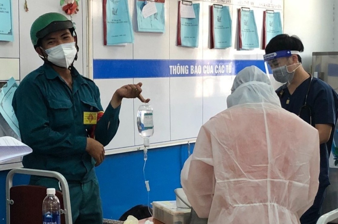 Chang trai vo tinh thanh gia treo chai nuoc bien o diem tiem vaccine hinh anh