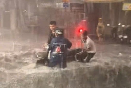 3 thanh nien lao ra giup nguoi la te xe trong mua lon o TP.HCM hinh anh