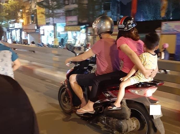 Cha me de con ngoi sau cung tren xe may, dau khong doi mu bao hiem hinh anh