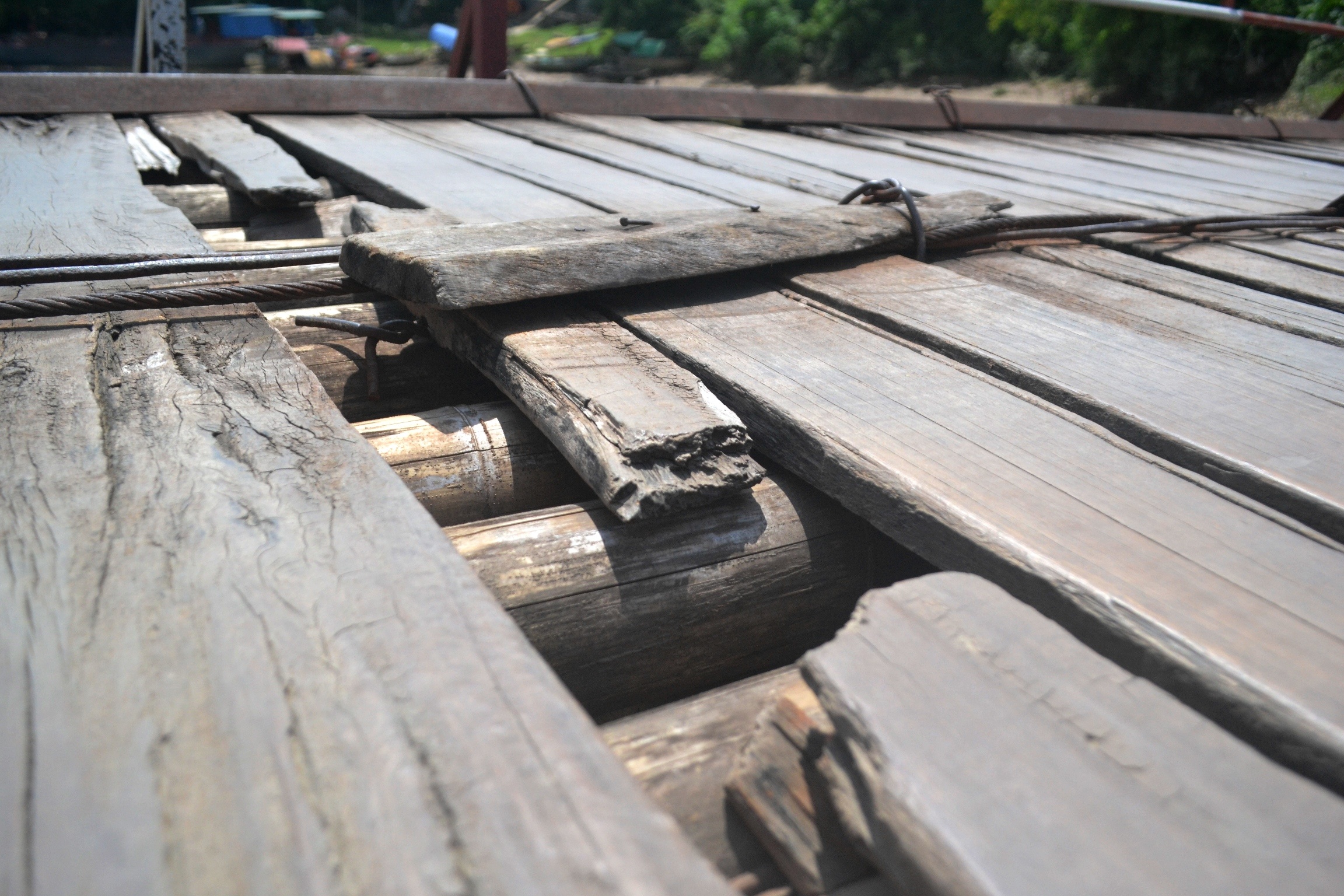 Nhiều thanh ván gỗ trên cầu bị mục, gãy, tạo thành các lỗ thủng lớn.