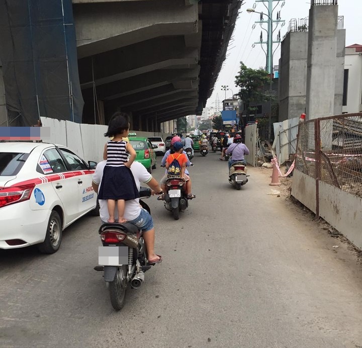 bé gái đứng trên yên xe máy đang đi ảnh 1 be gai dung tren yen xe may dang di anh 1