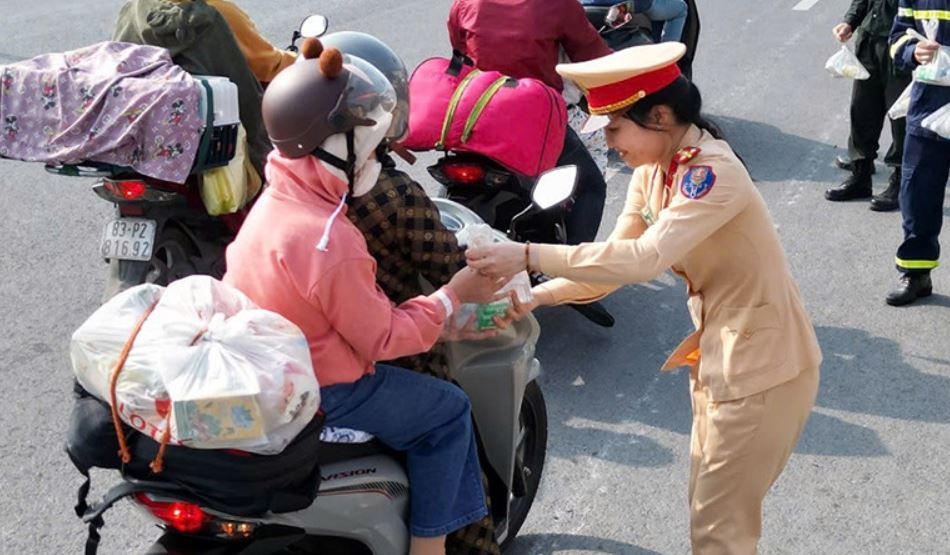 CSGT o mien Tay phat banh mi, sua, nuoc suoi cho nguoi ve que an Tet hinh anh