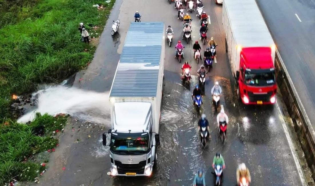 Tai xe dieu khien xe container chan dong nuoc cho xe may di qua hinh anh