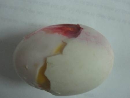Dịch đỏ tươi tụ ở một góc của quả trứng vịt đã được luộc chín.