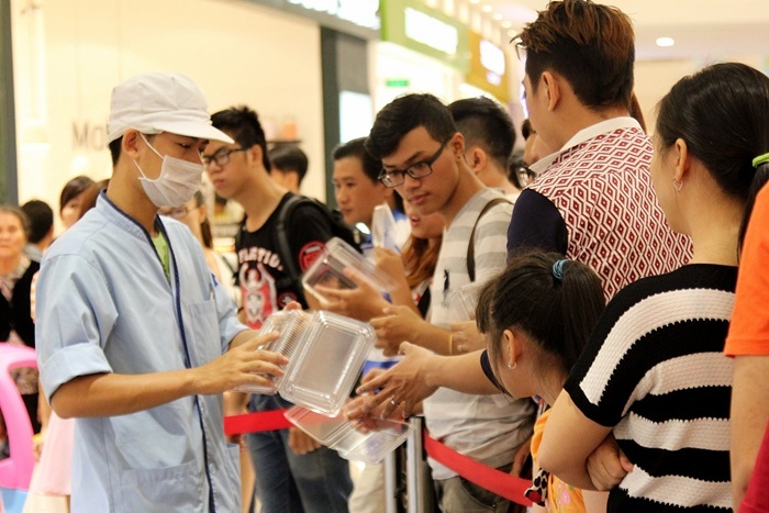 Nhân viên tiệm sushi phát hộp cho khách hàng đến lượt mua.