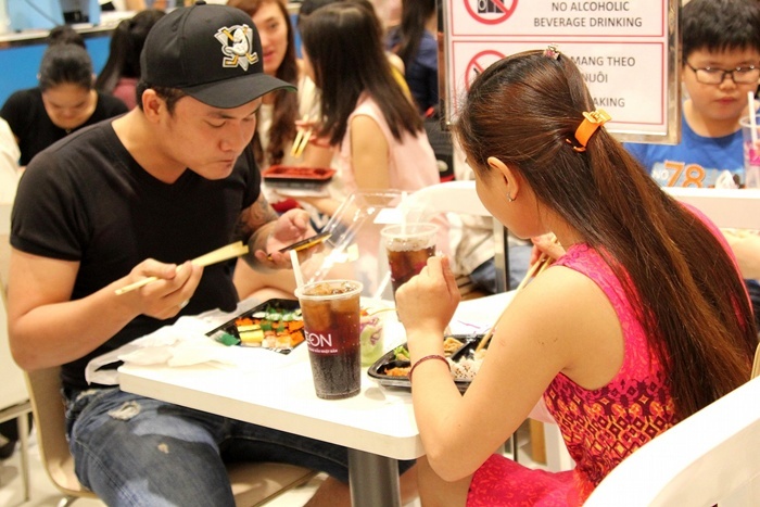 Khách hàng thưởng thức tại chổ món sushi nóng hổi vừa ra lò, sau khi phải đứnghàng tiếng đồng hồ để mua được món ăn yêu thích này.