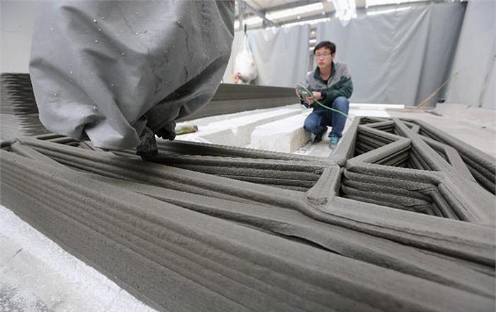 Một công nhân đang sử dụng bảng điều khiển để tiến hành in những bức tường bằng máy in 3D. 