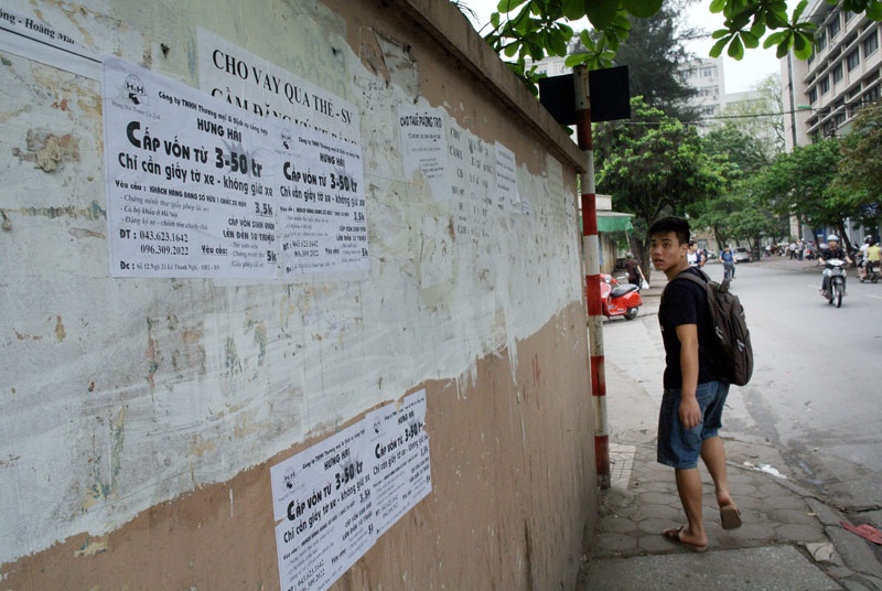 Quảng cáo tín dụng đen dán chồng chéo trên bờ tường trên phố Tạ Quang Bửu, nơi rất đông sinh viên qua lại.