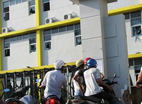 Công nhân Mỹ Thanh đang đọc thông báo. Phía trong là những cửa sổ bị đập vỡ tan hoang.