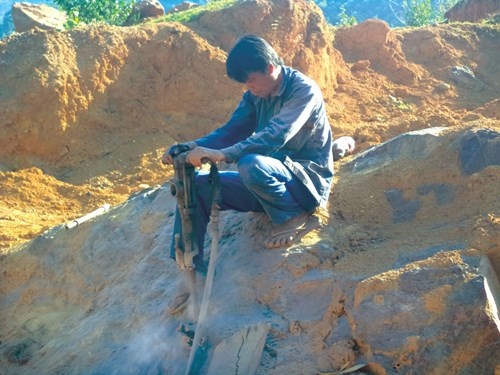 Một thợ khoan đang cố gắng tách hòn đá có đường kính chừng 3 mét.