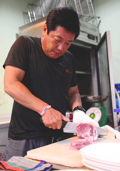 Ông Woo Sang Ho đang thái thịt.
