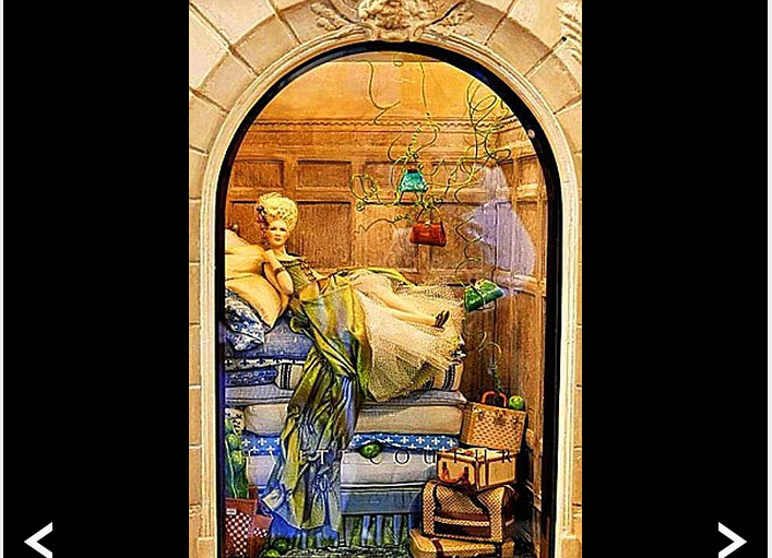 Và đây là một người mẫu, diện bộ đầm diêm dúa, tạo dáng bên trên chồng đệm và túi xách, va li của một cửa tiệm khác. Tất cả các mẫu vải dùng trong nhà búp bê đều được sơn thủ công.