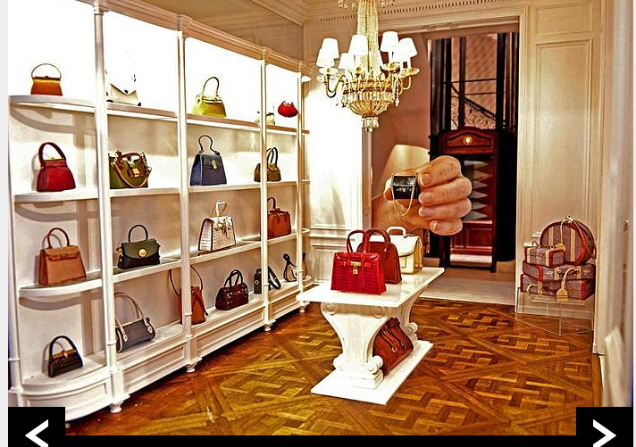 Một bức ảnh độc đáo với bàn tay thật đang cầm một chiếc túi xách hàng hiệu phiên bản mini trong tiệm bán đồ hiệu. Được biết, cặp đôi nghệ sĩ đã dành suốt 30 năm qua để sáng tạo những nhà búp bê vô cùng ấn tượng.