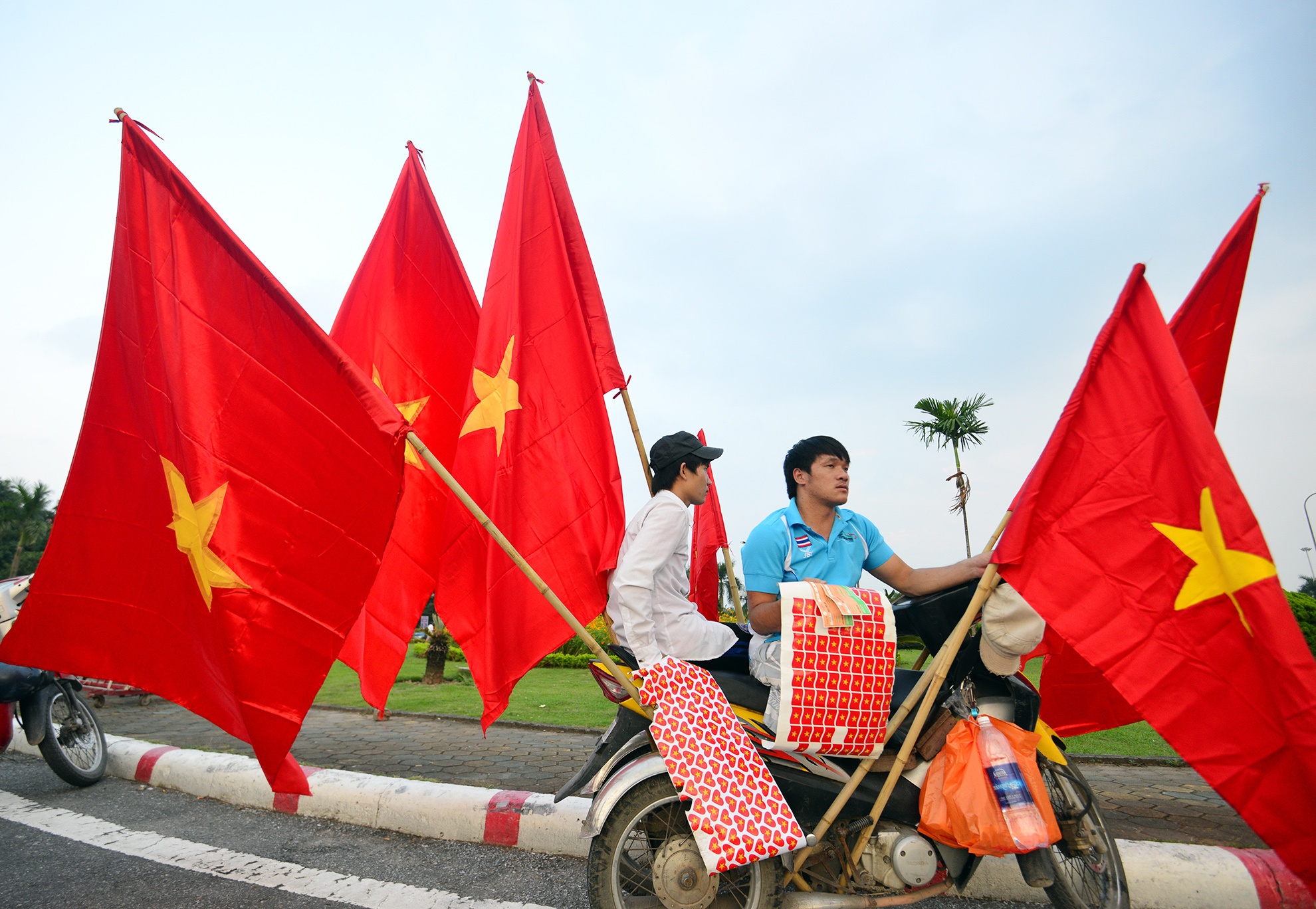Nam thanh niên bán cờ tổ quốc tại quảng trường SVĐ Mỹ Đình, anh cho biết. Từ 13h đã bán được 6 lá cờ cỡ to có giá 60.000 đ, những tấm băng rôn nhỏ đeo tay và trán có giá 10.000 đ.
