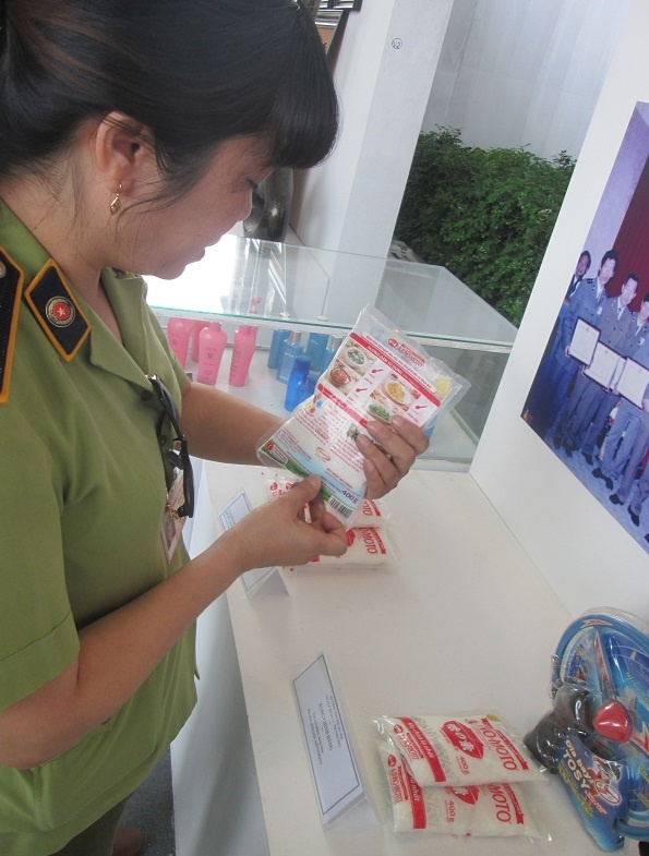 Một đại diện của Chi cục Quản lý Thị trường Hà Nội cầm gói bột ngọt Ajinomoto trên tay, giới thiệu các nhận biết cho người tiêu dùng về hàng thật, hàng giả