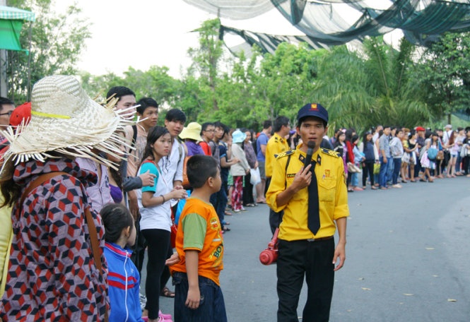 Nhân viên điều hành trạm xe đưa đón phải dùng loa yêu cầu khách đi bộ vì xe phục vụ không đủ.