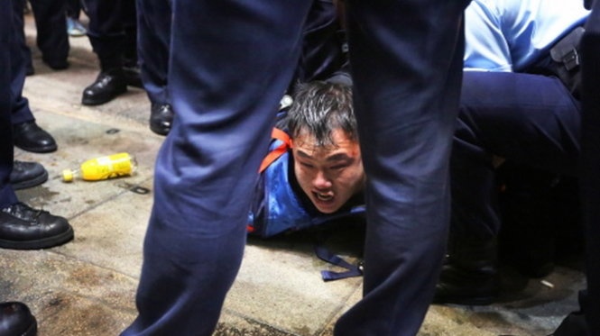 Một người biểu tình bị cảnh sát ép nằm sát đất .