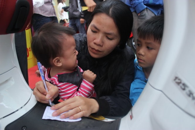 Đúng 17g, khi chương trình bốc thăm diễn ra, hàng trăm người dân đúng trên lề đường, thậm chí có người trèo lên xe máy, đu lên trụ điện để theo dõi. Những đứa trẻ được bố mẹ đưa đi bốc thăm “Giờ vàng – giá sốc” chiều 29-11 tại TP.Buôn Ma Thuột, Đắk Lắk.