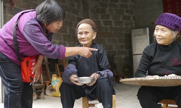 Du khách hỏi thăm cụ Huang Meijan 99 tuổi (trái) và người cháu gái Huang Meije (76 tuổi) tại ngôi làng trăm tuổi ở tỉnh Quảng Tây, Trung Quốc.