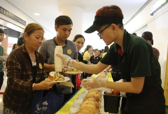 Mọi người xếp hàng trật tự để nhận bánh mì miễn phí.